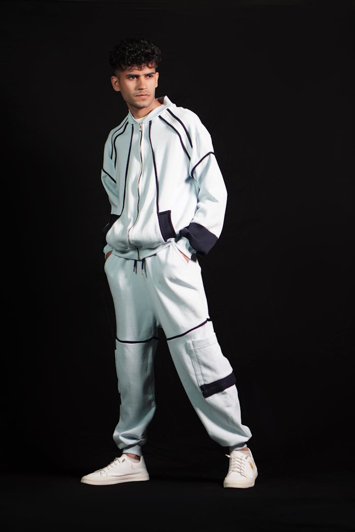 Portrait of a man in contemporary sportswear, standing confidently against a black background.