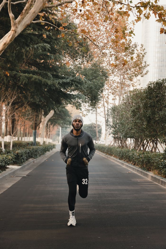 A man jogging on a scenic path in Abuja with autumn leaves and cityscape in the background.